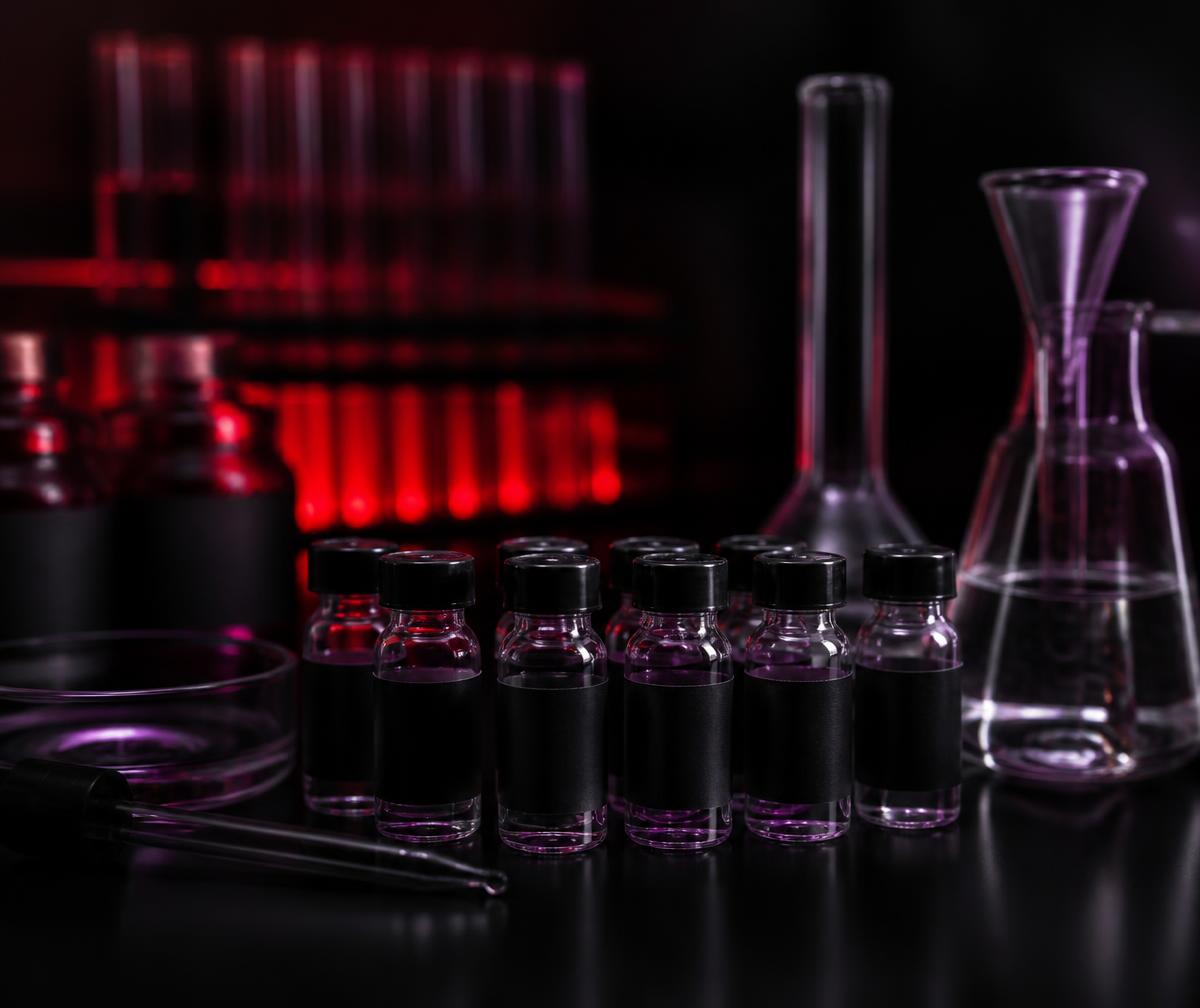 Rows of black-labelled research vials and laboratory glassware under red illumination